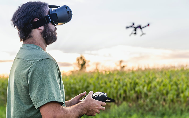 Man wearing a virtual reality goggles headset is flying a drone. 