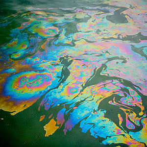 Colorful patterns in an oil spill on polluted water.