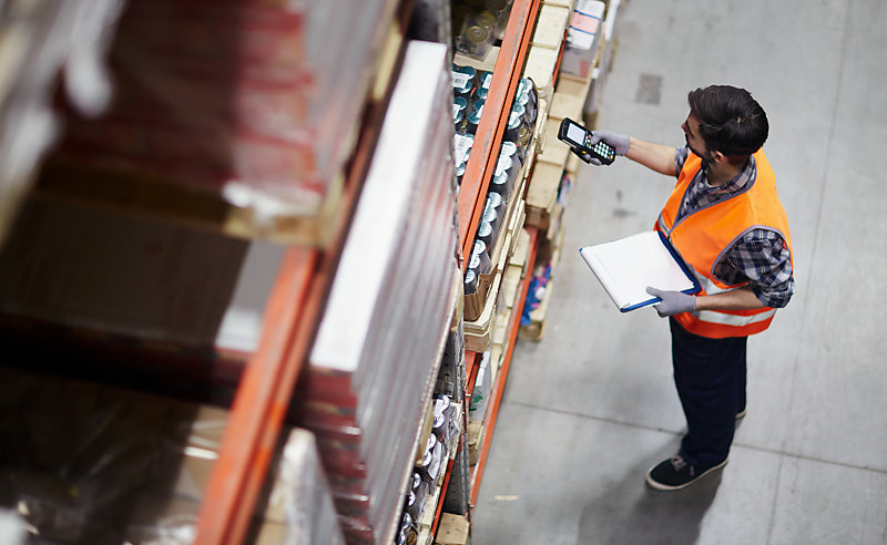 A worker checking barcodes in a warehouse. 