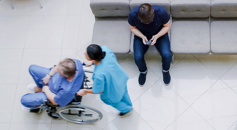 High-angle shot of a hospital lobby with a nurse pushing a patient in a wheelchair.