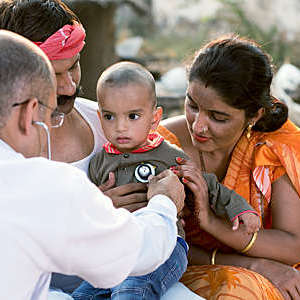 Paediatrician examines a sick baby boy during a home visit in a village.