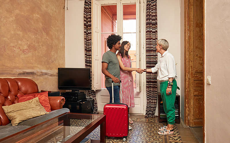 Couple with a suitcase, shaking hand with the rented apartment owner. 