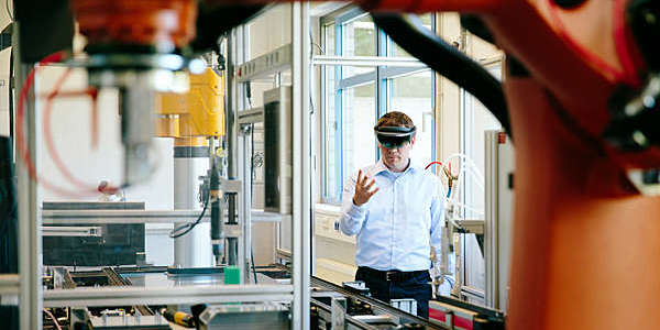 Engineer works with a HoLoLens headset to place a virtual robotic arm into the production line.