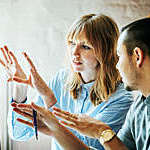 Two startup business colleagues problem-solving at a computer together in the office.
