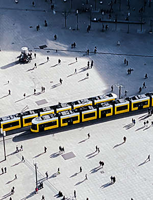 Aerial view of two yellow trams crossing on a main city square.