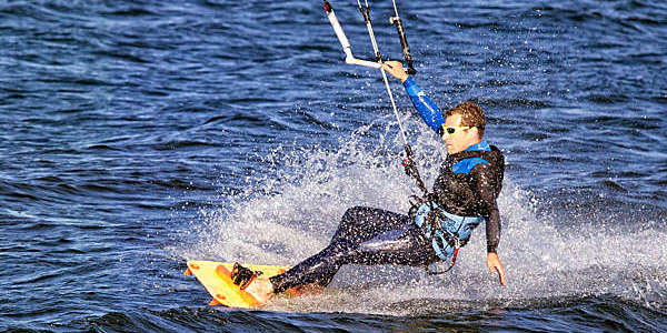 Close shot of man kitesurfing on a lake.