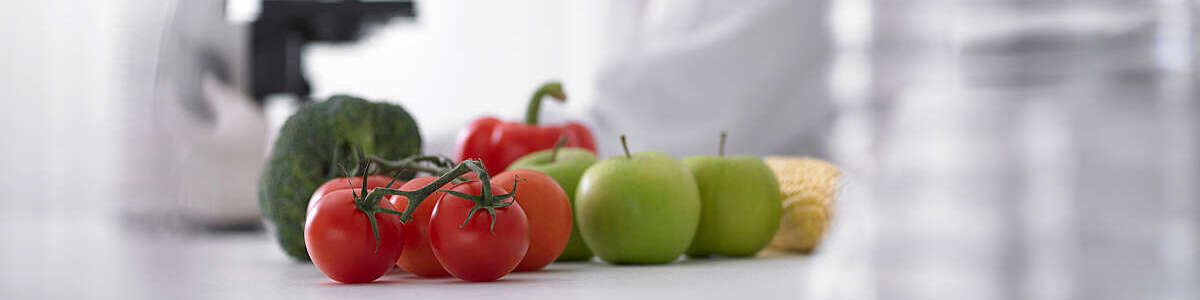 Fruits and vegetables next to scientist using microscope.