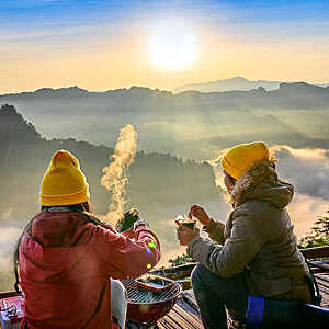traveller tourist or backpackers are, enjoy hot drink and breakfast meal in morning with the scenery of mist and fog flowing in between the hills in back ground