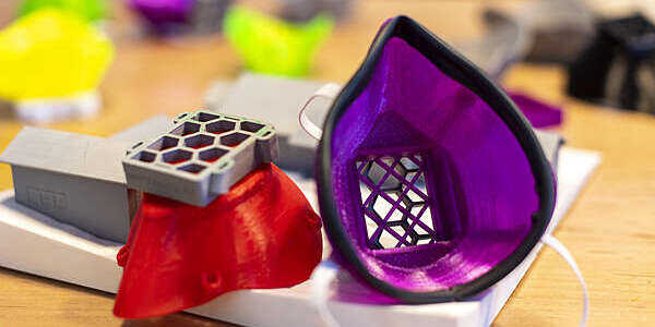 Close-up of brightly coloured red and mauve respirator masks created on a 3D printer.